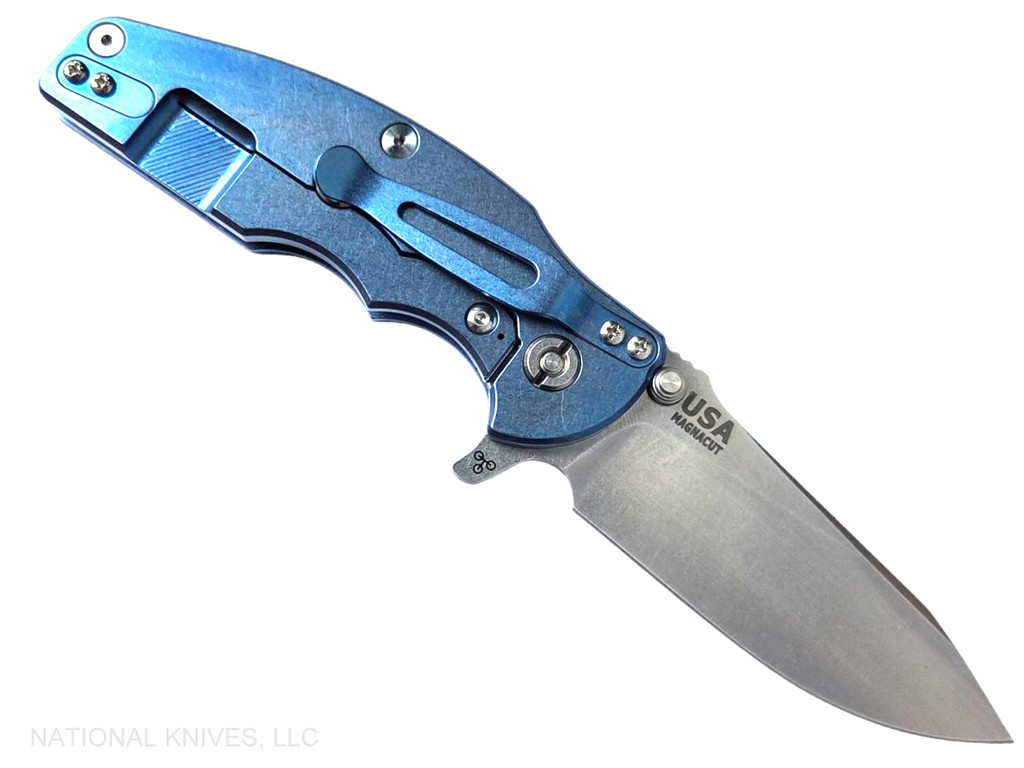 Rick Hinderer Knives Jurassic Hollow Grind Slicer folding knife with flipper tab - shown open lock side.  Stonewash MagnaCut stainless steel plain edge blade.  Blue - black G-10 handle scale with stonewash blue titanium lock side.  Model KJURSLHO.
