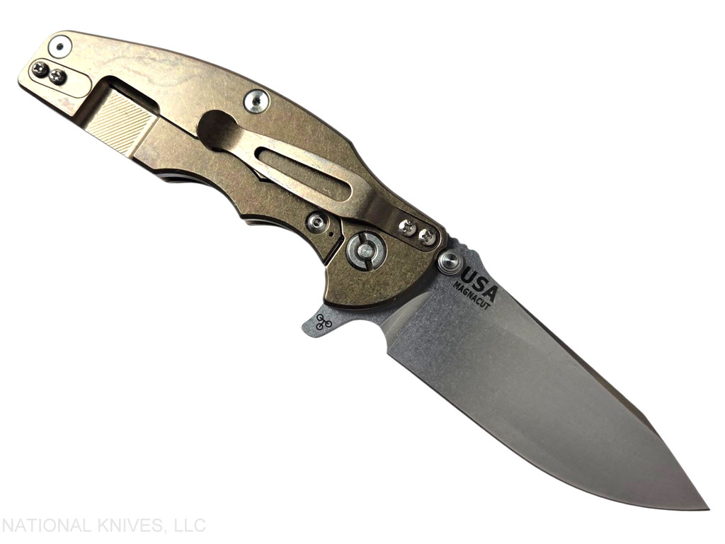 Rick Hinderer Knives Jurassic Hollow Grind Slicer folding knife with flipper tab - shown open lock side.  Stonewash MagnaCut stainless steel plain edge blade.  OD Green G-10 handle scale with stonewash bronze titanium lock side.  Model KJURSLHO.