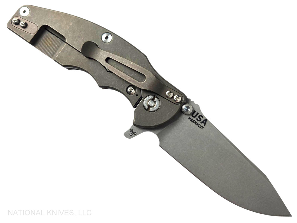 Rick Hinderer Knives Jurassic Hollow Grind Slicer folding knife with flipper tab - shown open lock side.  Working Finish MagnaCut stainless steel plain edge blade.  Translucent Green G-10 handle scale with Battle Bronze titanium lock side.  Model KJURSLHO.