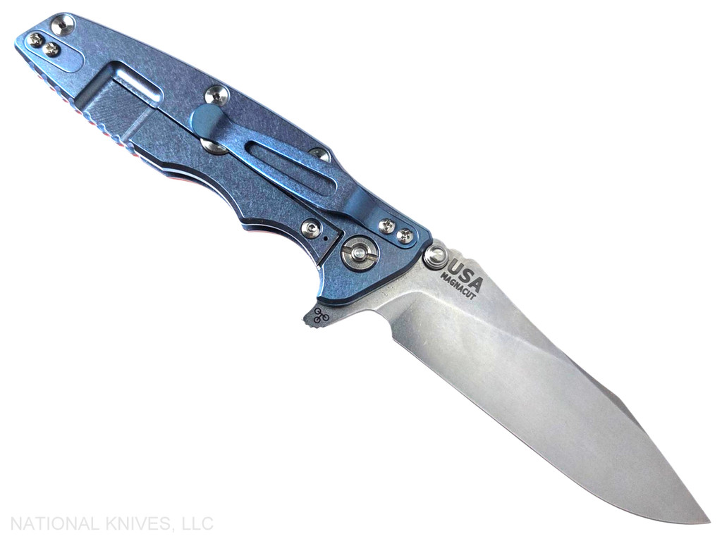 Rick Hinderer Knives Skinny Eklipse Slicer folding knife with flipper tab - shown open - lock side.  Stonewashed 3.5" hollow grind MagnaCut stainless steel plain edge blade.  Orange G-10 handle scale with stonewash blue lock side.  Model KEK35SKSLHO