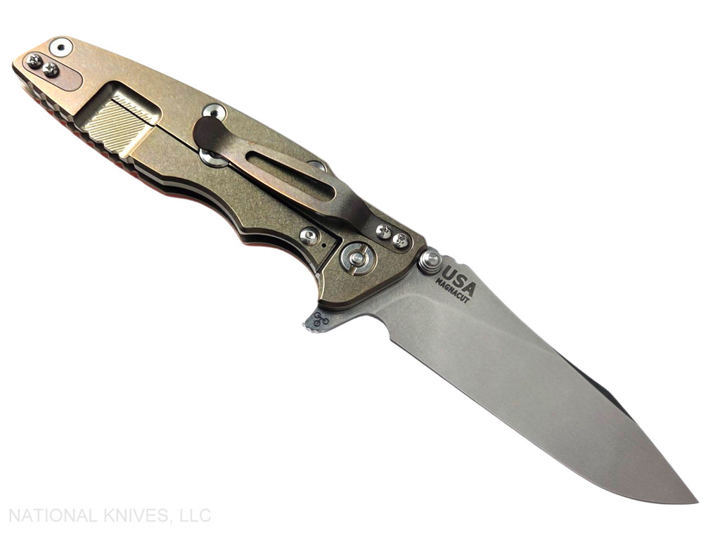 Rick Hinderer Knives Skinny Eklipse Slicer folding knife with flipper tab - shown open - lock side.  Stonewash 3.5" hollow grind MagnaCut stainless steel plain edge blade.  Orange G-10 handle scale with stonewash bronze lock side.  Model KEK35SKSLHO