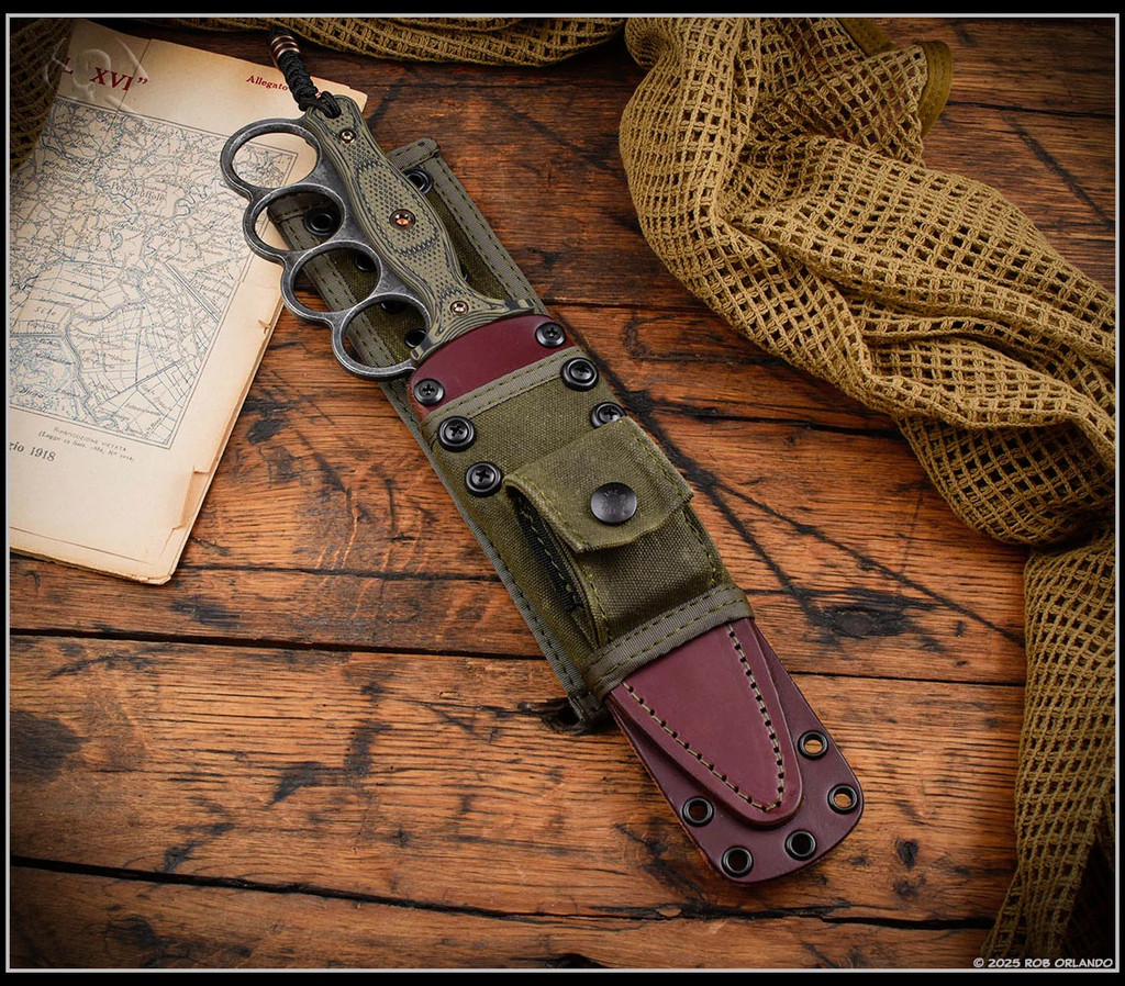 RMJ Tactical Trench Raider - shown in sheath obverse. Acid Etch 3V steel double plain edge blade.  Dirty Olive G-10 handle scales.  Model K-TR-3V-GB-DO-OX.