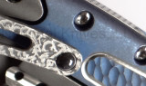 Todd Begg Knives Bodega 2.0 folding knife with flipper tab - shown close up of pocket clip.  2-tone N690 stainless steel plain edge blade.  Blue titanium handle.
For reference only.