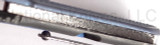 Todd Begg Knives Bodega 2.0 folding knife with flipper tab - shown close up of back spacer.  2-tone N690 stainless steel plain edge blade.  Blue titanium handle.
For reference only.