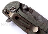Rick Hinderer Knives Battlefield Pick Up XM-18 3.5" Harpoon Spanto folding knife with thumb stud and flipper tab - close up of lock side pivot shown.  M390 stainless steel plain edge blade.  OD green G-10 handle with titanium lock side.  Model K25520SP00.
For reference only.