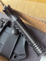 Used RMJ Tactical Peregrine fixed blade knife - bottom view of handle shown.  Tungsten Cerakote Nitro-V stainless steel plain edge blade.  Black G-10.