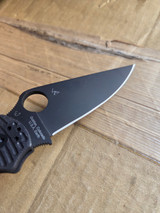 Used Spyderco Paramilitary 2 Salt folding knife with thumb hole - close up of pocket clip side blade shown.  Black MagnaCut stainless steel plain edge blade.  Black G-10 handle.  Model C81GMCBKP2.