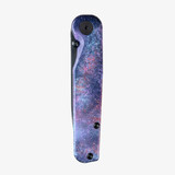 Tactile Knife Co Seasonal Release Deep Space Rockwall folding knife with thumb stud - shown closed presentation side.  Black MagnaCut stainless steel plain edge blade.  Deep Space themed titanium handle.
For reference only.
