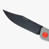 Tactile Knife Co 8-Bit Bexar limited edition slip joint knife with nail nick - close up of blade logo side.  Black MagnaCut stainless steel plain edge blade.  Gray and orange titanium handle.  Model 20-BX-MCDL-TTDL
For reference only.