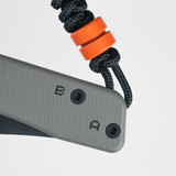 Tactile Knife Co 8-Bit Bexar limited edition slip joint knife with nail nick - close up of lanyard side view.  Black MagnaCut stainless steel plain edge blade.  Gray and orange titanium handle.  Model 20-BX-MCDL-TTDL
For reference only.