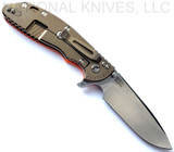 Rick Hinderer Knives XM-24 Spear Point folding knife with thumb stud and flipper tab - shown open lock side.  Stonewash S45VN stainless steel plain edge blade.  Orange G-10 handle with stonewash bronze lock side.  Model KXM40SPE.