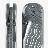 Tactile Knife Co Topographical Rockwall folding knife with thumb stud - close up of thumb stud and pivot and thumb stud - two views.  Stonewashed MagnaCut stainless steel plain edge Tanto blade.  Topographical titanium handle.  Model 20-RT-MCTN-TOPO.