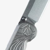 Tactile Knife Co Topographical Rockwall folding knife with thumb stud - close up of pivot and thumb stud.  Stonewashed MagnaCut stainless steel plain edge Tanto blade.  Topographical titanium handle.  Model 20-RT-MCTN-TOPO.
