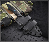 RMJ Tactical Ratatosk fixed blade knife with blue hardware installed - shown in sheath obverse.  Graphite Black Cerakote Nitro-V stainless steel plain edge blade.  Black Micarta handle.  Model K-RT-GB-LM-BK.