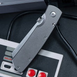 Tactile Knife Co Mariner 2 folding knife with thumb disk - shown closed presentation side.  Stonewash MagnCut stainless steel plain edge blade. Titanium handle.  Model 20-MAR-MC01-TUTT
