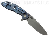 Rick Hinderer Knives XM-18 Skinny Slicer with thumb stud and flipper tab - shown open lock side.  Working Finish Magnacut stainless steel, hollow ground, plain edge blade.  Black G-10 handle with Battle Blue lock side. 