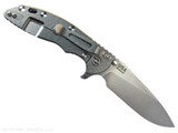 Rick Hinderer Knives XM-18 Skinny Slicer with thumb stud and flipper tab - shown open lock side.  Stonewash Magnacut stainless steel, hollow ground, plain edge blade.  Blue - Black G-10 handle with stonewash lock side. 