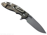 Rick Hinderer Knives XM-18 3.5" Slicer Hollow Grind folding knife with thumb stud and flipper tab - shown open lock side.  Working Finish 20CV stainless steel plain edge blade.  Black G-10 handle with Battle Bronze lock side.  Model KXM35SLHO.