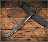 RMJ Tactical Wyvern short sword - shown atop sheath tip pointed lower left.  Acid Etched 3V steel plain edge blade.  Black G-10 handle scales.  Model 3V-WY-AE-BK.
