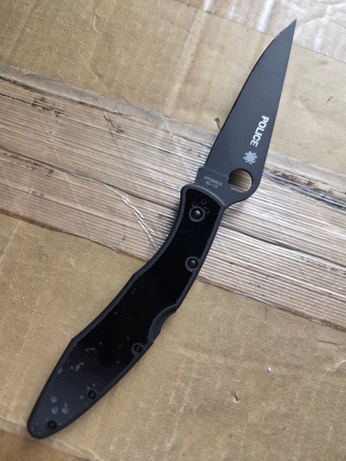 Used Spyderco Police folding knife with thumb hole - shown open presentation side.  Black VG-10 stainless steel plain edge blade.  Black stainless steel handle.  Model C07BKP.
