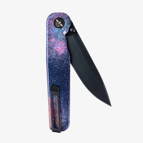 Tactile Knife Co Seasonal Release Deep Space Rockwall folding knife with thumb stud - shown partially open pocket clip side.  Black MagnaCut stainless steel plain edge blade.  Deep Space themed titanium handle.
For reference only.