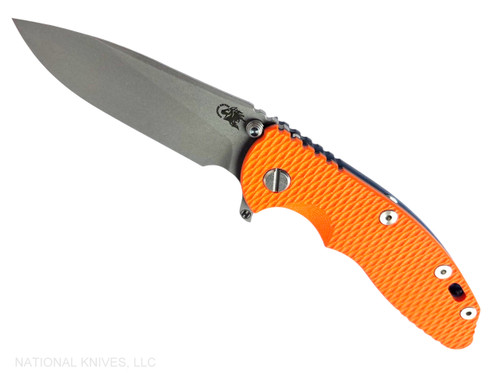 Rick Hinderer Knives XM-18 3.5" Slicer Hollow Grind folding knife with thumb stud and flipper tab - shown open presentation side.  Working Finish 20CV stainless steel plain edge blade.  Orange G-10 handle with Battle Blue lock side.  Model KXM35SLHO.