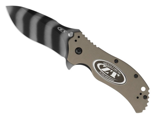 Zero Tolerance 0350OLTS20 assisted opening folding knife with flipper tab and thumb studs - open - logo side.  Tiger striped coated MagnaCut stainless steel plain edge blade.  FDE aluminum handle with 20 Year Anniversary inlay.  Model 0350FDETS20.
