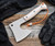 RMJ Tactical Explore More Bushcraft Axe - shown out of sheath.  Tungsten Cerakote 52100 steel blade.  Gray and orange G-10 handle. Model BC-EM.
For reference only.