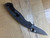 Used Spyderco Military 2 Salt folding knife with thumb hole - shown open pocket clip side.  Black CPM MagnaCut stainless steel plain edge blade.  Black G-10 handle.  Model C36GMCBKP2.