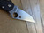 Blemished Spyderco Paramilitary 2 folding knife with thumb hole - close up of presentation side blade shown.  Satin CTS-BD1N stainless steel plain edge blade.  Black FRN handle.  Model C81PBK2.