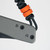Tactile Knife Co 8-Bit Bexar limited edition slip joint knife with nail nick - close up of lanyard side view.  Black MagnaCut stainless steel plain edge blade.  Gray and orange titanium handle.  Model 20-BX-MCDL-TTDL
For reference only.