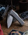 Chaves Knives Scapegoat Street folding knife with thumb stud - shown partially open presentation side.  Satin M390 stainless steel plain edge blade.  Stonewash titanium handle.  Model ST/SG/SWTI/BF.