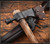 RMJ Tactical Patriot pipe tomahawk - shown close up of head in sheath obverse.  6150 steel plain edge head.  Ash wood handle.  Model T-PA-HK-NA.