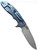 Rick Hinderer Knives XM-18 Skinny Slicer with thumb stud and flipper tab - shown open lock side.  Stonewash Magnacut stainless steel, hollow ground, plain edge blade.  Translucent Green G-10 handle with stonewash blue lock side. 