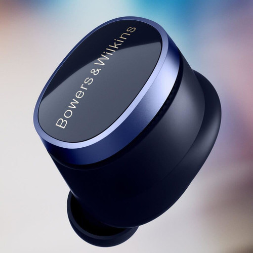 Single Bowers & Wilkins Pi8 earbud in Midnight Blue, angled close-up showing blue metallic ring and gold logo on gradient background
