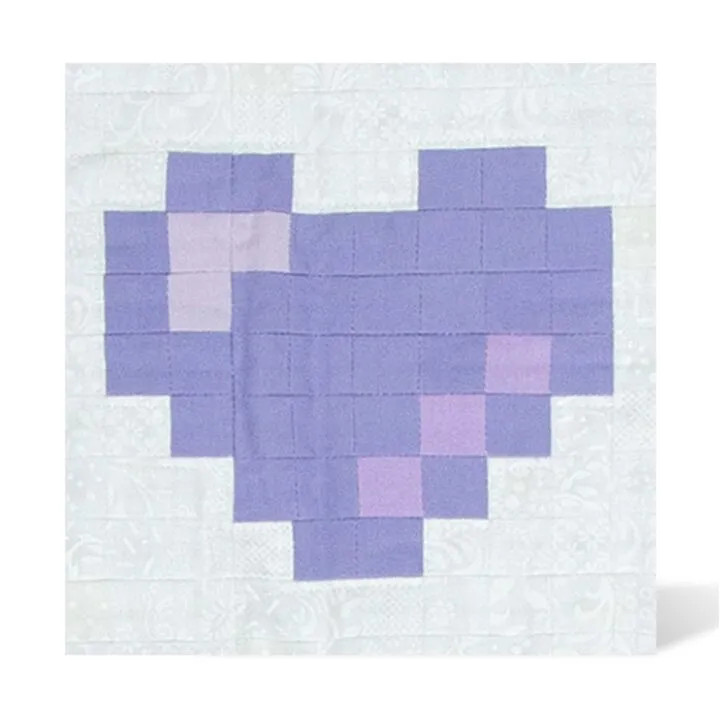 Purple patchwork heart quilt on a white textured fabric background.