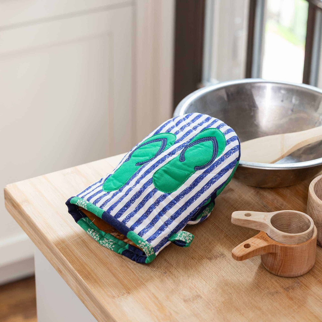 Quilted oven mitt with a flip-flop design on a wooden kitchen counter.
