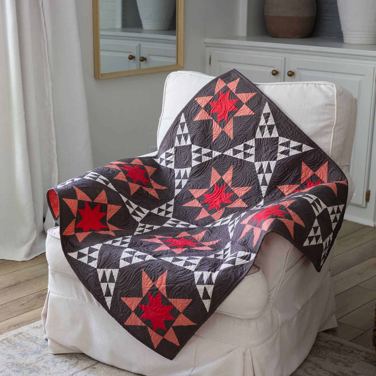 A vibrant star-patterned quilt draped over a white armchair in a cozy room.