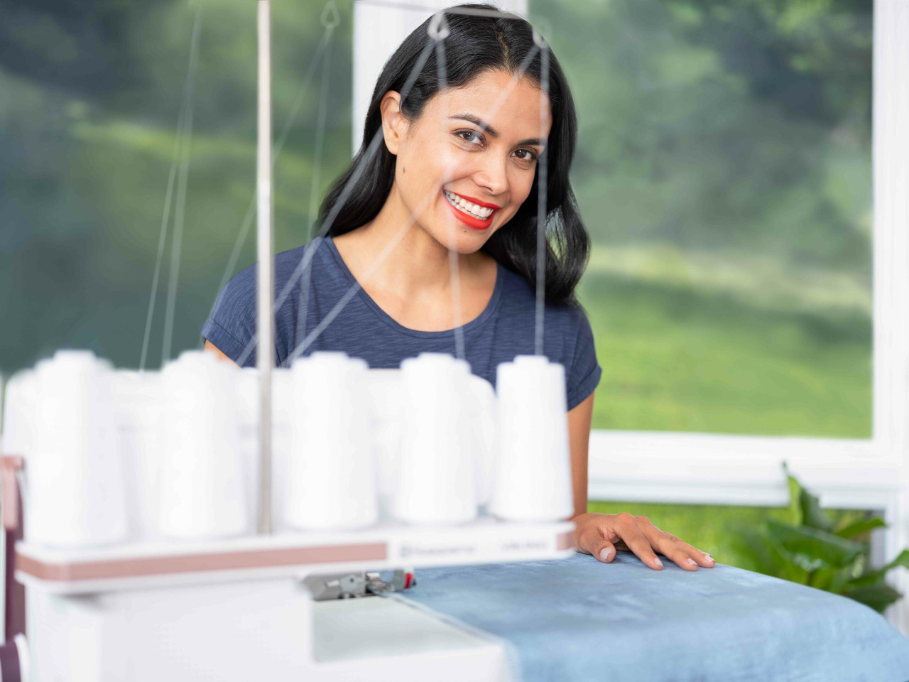 Husqvarna Viking serger white thread spools blue fabric bright workspace window view