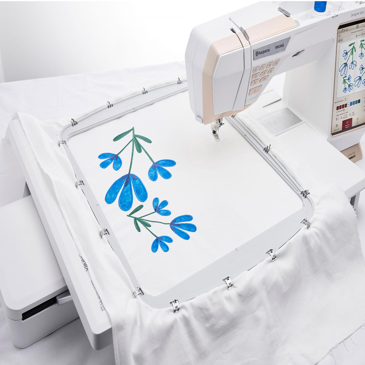 Modern embroidery machine creating a floral design on white fabric.