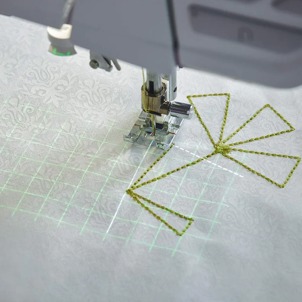 Sewing machine embroidery with green thread on patterned white fabric.