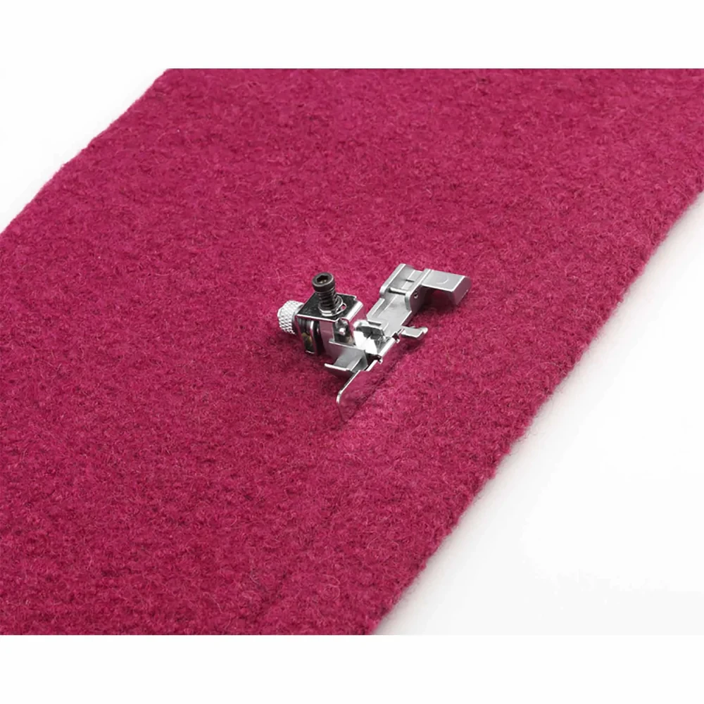 Sewing machine foot on burgundy fabric for precise stitching.