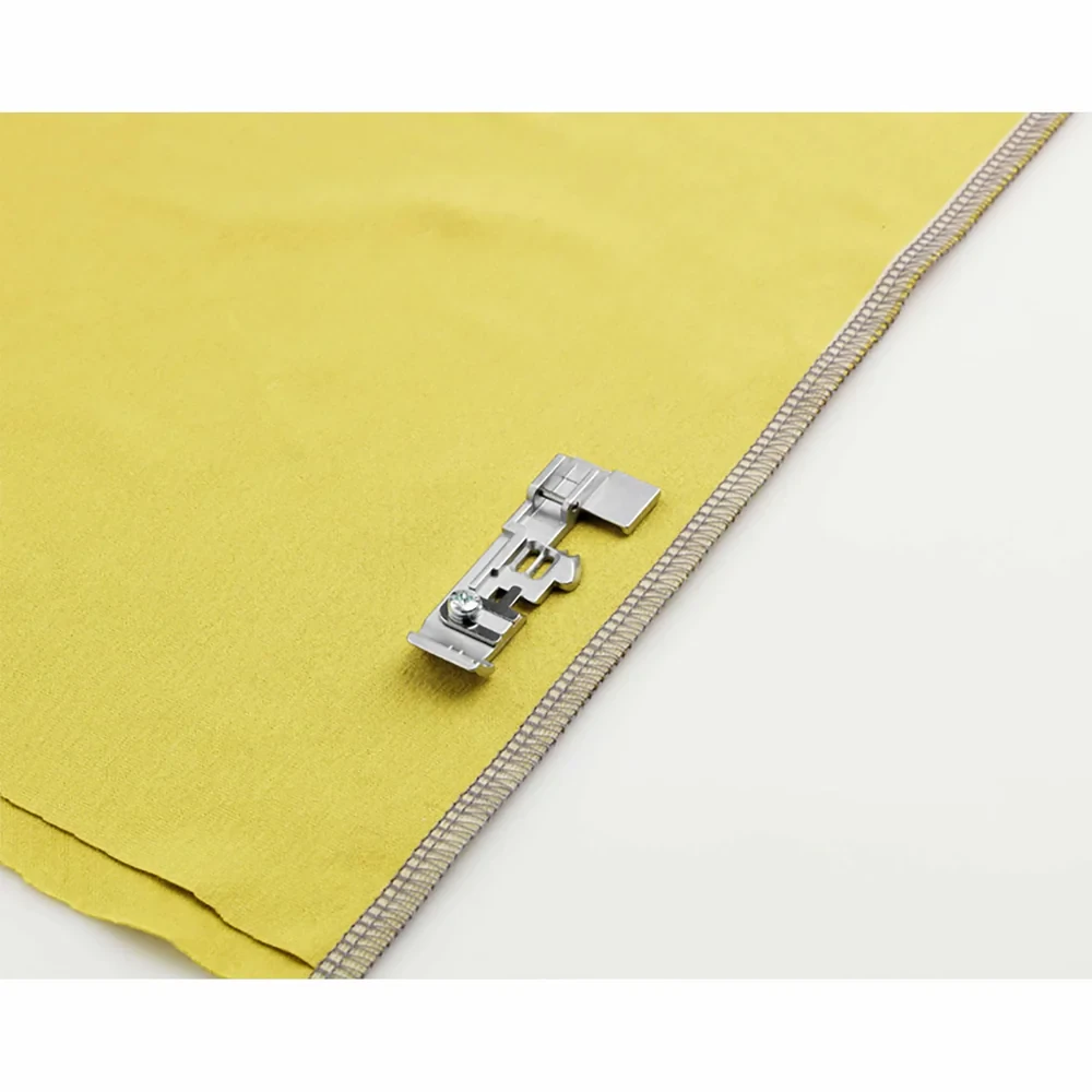 Sewing machine foot on yellow fabric edge highlighting stitching precision.