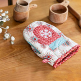 Quilted oven mitt with festive design on a wooden kitchen table.