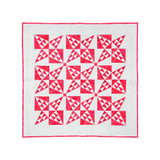 Red and white geometric quilt pattern showcasing precise fabric cutting artistry.