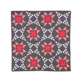 Quilt with red star patterns and geometric shapes on a dark background.