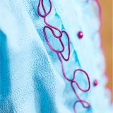 Close-up of blue patterned fabric with pink decorative stitching.