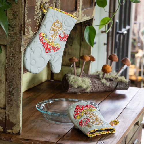 Quilted oven mitts with floral patterns displayed on a rustic wooden table.