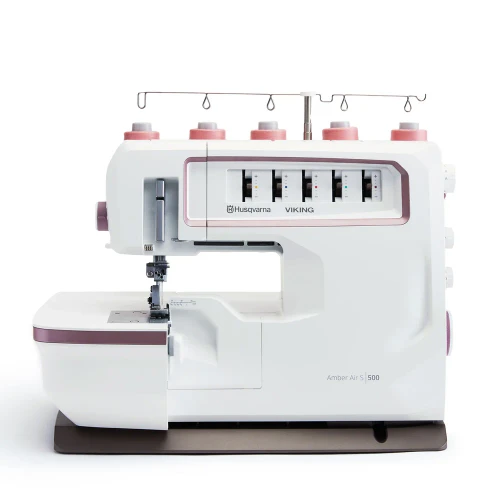 White sewing machine with thread spools displayed against a plain background.