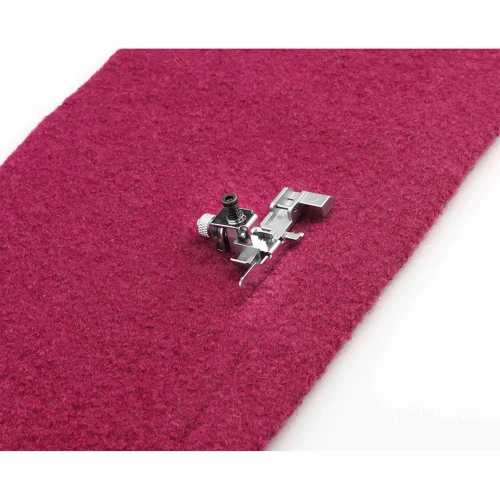 Sewing machine foot on burgundy fabric for precise stitching.